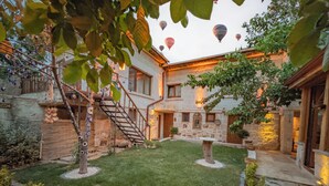 A courtyard with a well-maintained lawn, stone walls, and a wooden staircase leading to an upper level.