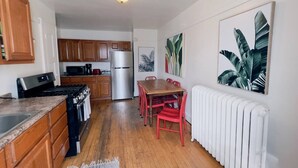 Una cocina con armarios de madera, un refrigerador de acero inoxidable, una estufa y una mesa de comedor con sillas rojas.