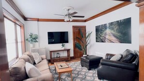 Una sala de estar con un sofá, una mesa de centro, un televisor y un cuadro.