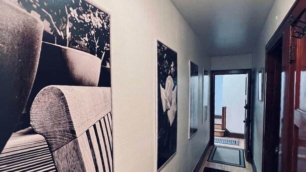 Un pasillo con un felpudo a rayas blanco y negro, un banco de madera y obras de arte enmarcadas en las paredes.