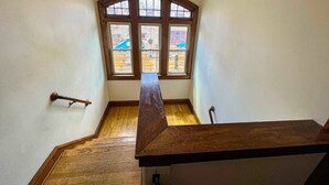 Una escalera de madera con barandilla, que conduce a una habitación con un amplio ventanal y vistas a un patio de juegos al aire libre.
