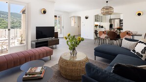 Ett modernt vardagsrum med en soffa, en tv och en matplats med stolar och ett bord.