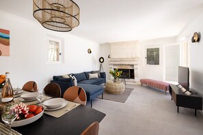 A modern living room with a sofa, dining table, and a fireplace.