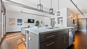A modern kitchen with a large island, stainless steel appliances, and pendant lighting. - The Badlands Loft  (Rapid City)