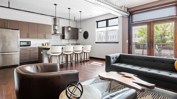 A modern kitchen with a central island, bar stools, and a large window providing natural light. - The Badlands Loft  (Rapid City)