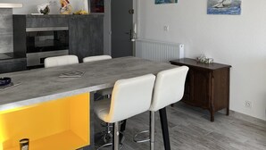 A modern kitchen with a grey countertop, white chairs, and a wooden dining table.