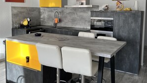 A modern kitchen with a central island, bar stools, and a built-in oven.