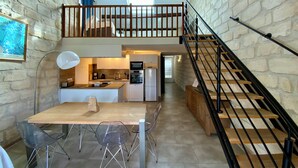 A spacious kitchen with a dining area, a staircase, and a loft bedroom.