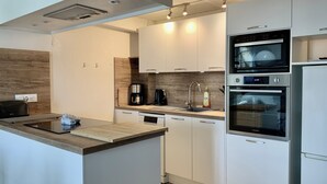A modern kitchen with white cabinets, a built-in oven, a coffee maker, and a toaster.