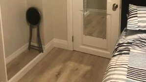Ein Schlafzimmer mit Bett, Kleiderschrank mit Kleidung und einer Tür mit Spiegel.