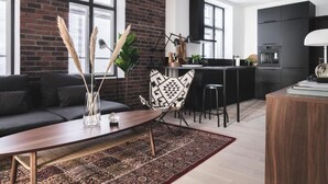 A modern living room with a dark sofa, a wooden coffee table, and a patterned rug. - Stay Bryggen - Serviced Apartments (Bergen)