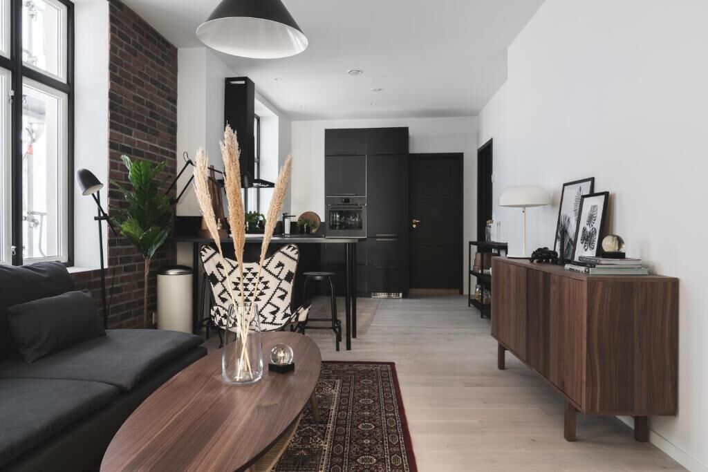 A modern living room with a dark sofa, a wooden coffee table, and a decorative vase.