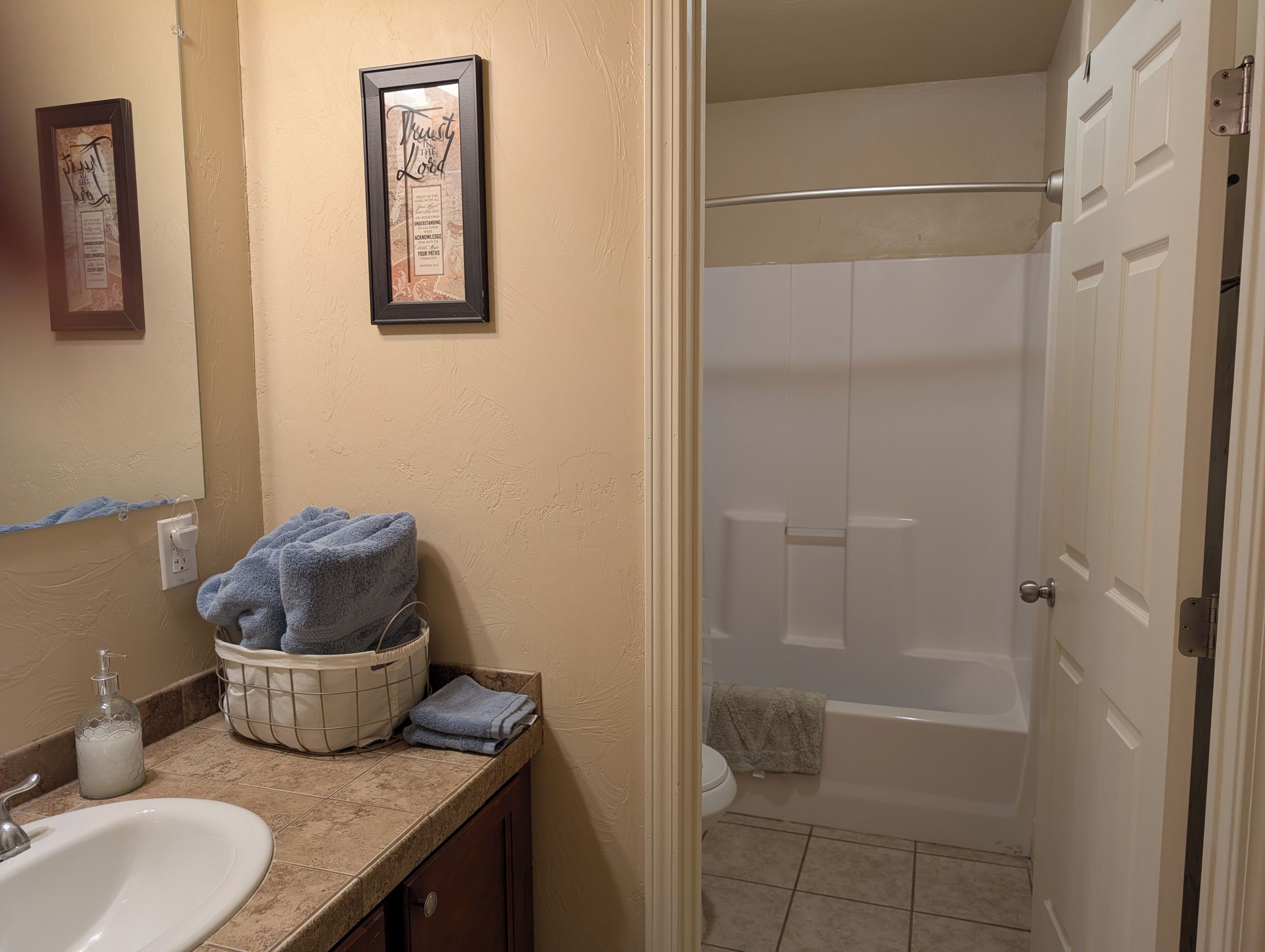 Une salle de bain équipée d’un lavabo, d’un miroir, de tableaux encadrés, de serviettes et d’une baignoire.