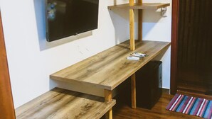 A room with a wooden bench, a television mounted on the wall, and a door with a striped mat. - VILLA CRIS (Fernando de Noronha)