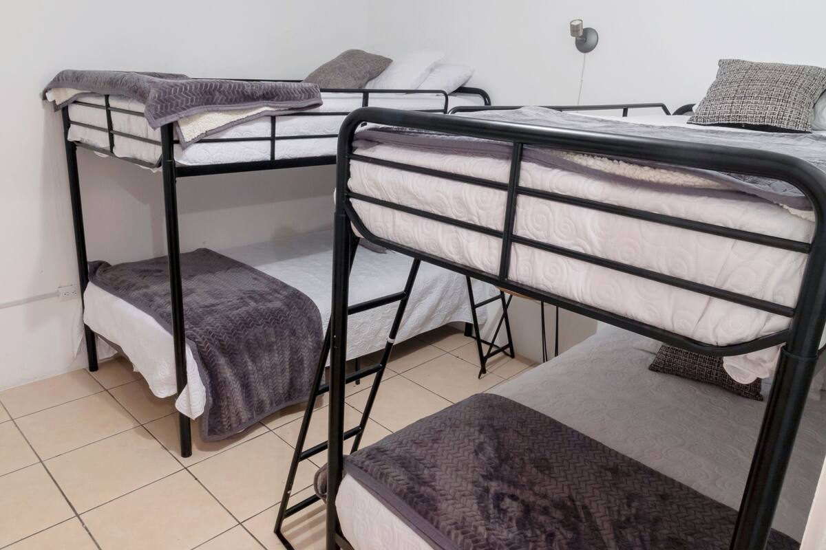 A dormitory room with bunk beds, a desk, and a lamp.