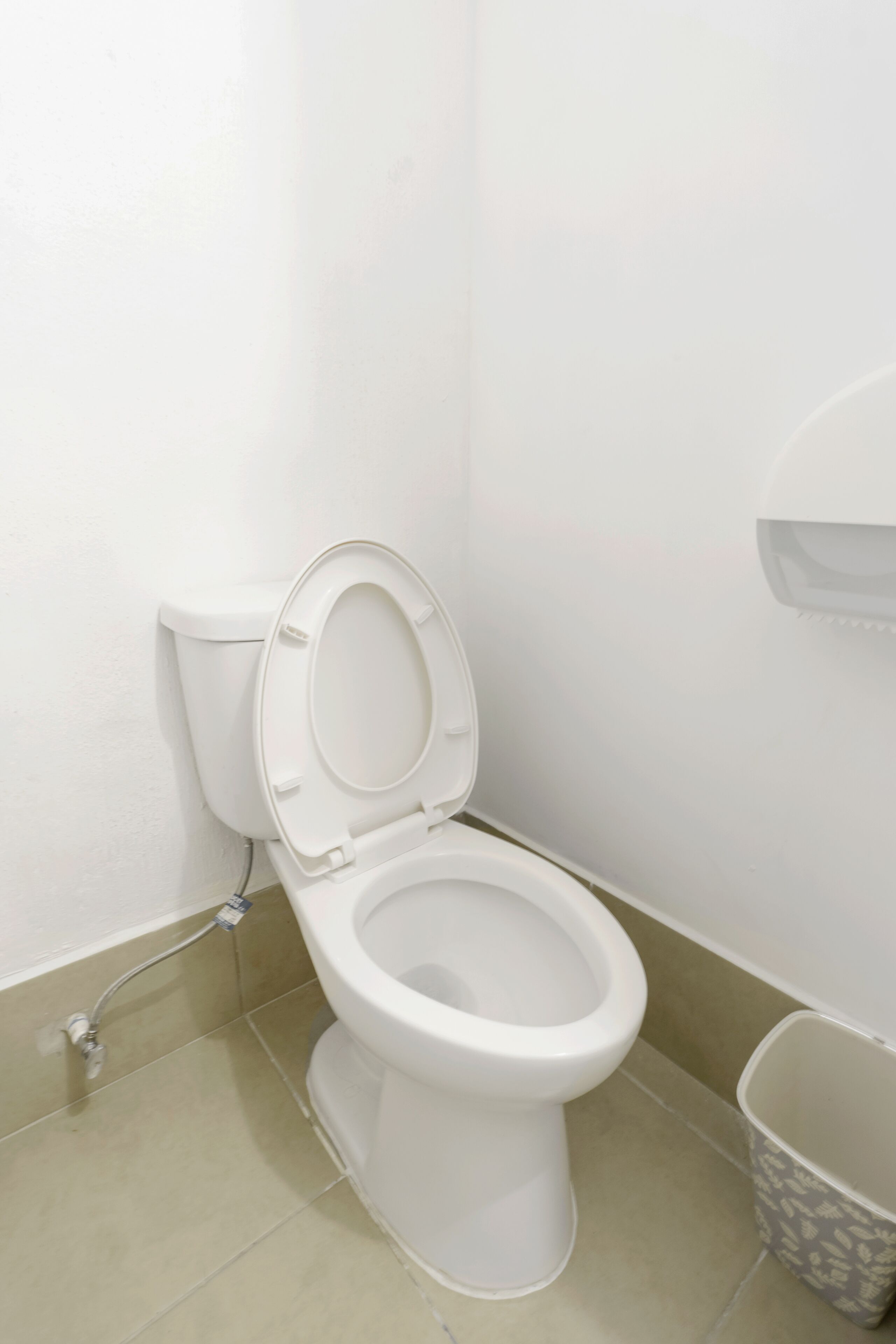 Eine weiße Toilette mit geschlossenem Deckel, einem an der Wand montierten Spülhebel und einem am Boden befestigten Spülknopf.
