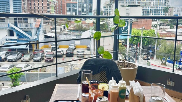 A dining table with food and drinks, a potted plant, and a view of a cityscape with buildings and a construction crane. - Hotel Citadin Z4 (Guatemala City)