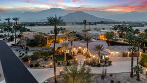A large, well-lit resort with multiple buildings, palm trees, and a mountainous backdrop.