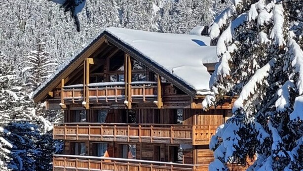 A multi-story wooden lodge with balconies, surrounded by snow-covered trees and mountains. - 2 bed Apt in Courchevel 1650, Doorstep skiing - Courchevel, Meribel, Val Thorens (Courchevel)