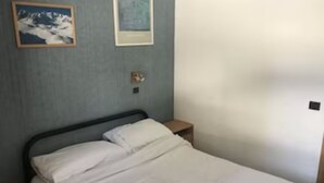A bedroom with a bed, a nightstand, and two framed pictures on the wall. - 2 bed Apt in Courchevel 1650, Doorstep skiing - Courchevel, Meribel, Val Thorens (Courchevel)