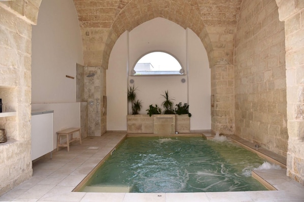 A spa area with a pool, stone walls, and a bench.
