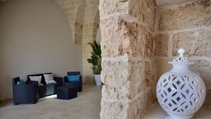 A stone wall, a white decorative urn, and a seating area with sofas and cushions. - LeVolte luxury apartment and pool (Sternatia)