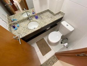 A bathroom with a granite countertop, two sinks, a toilet, and a mirror. - House in Praia do Forte with a private lagoon. (Açu da Torre)