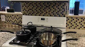 Una cocina con un microondas blanco, estufa y ollas.