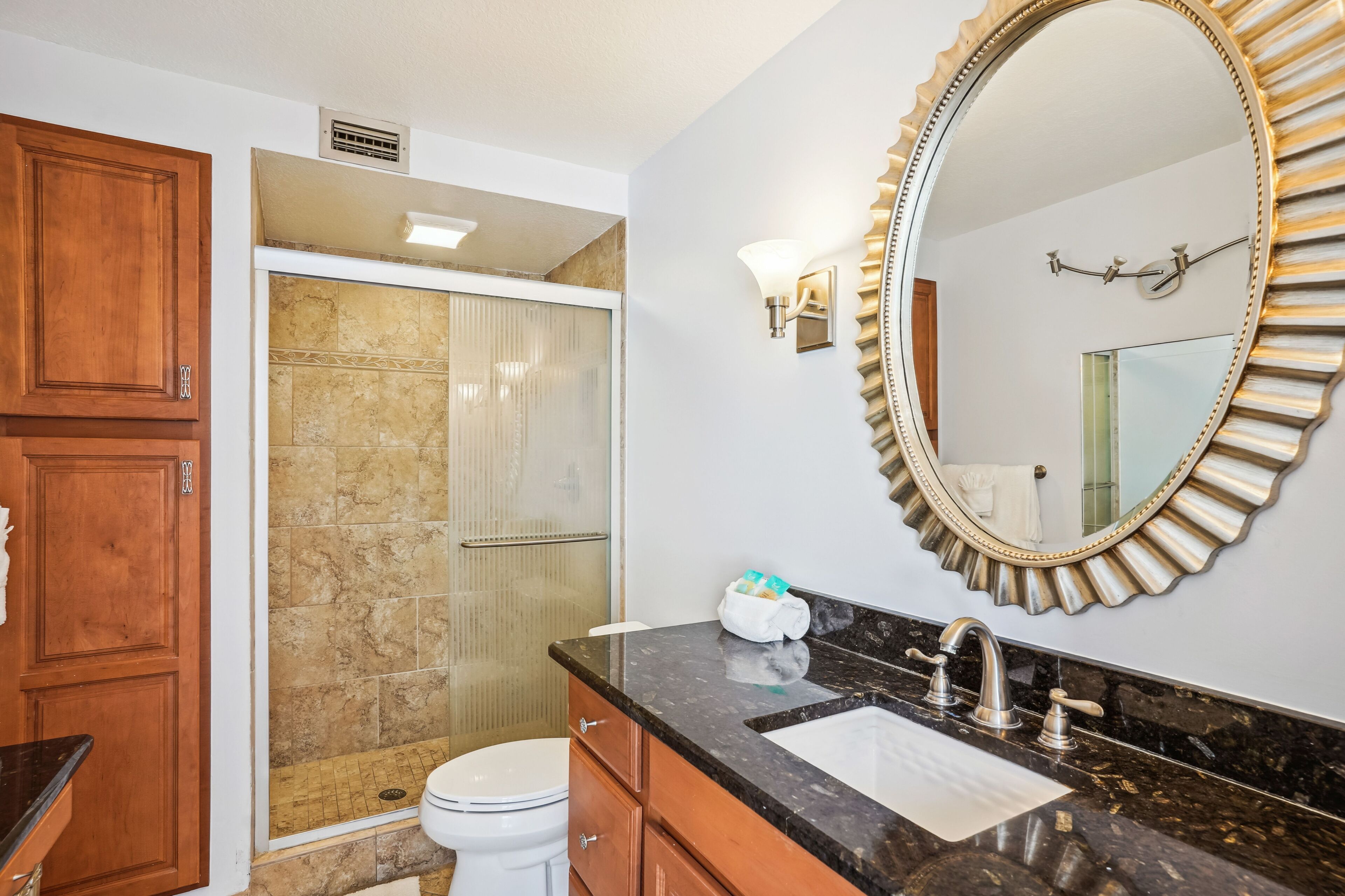 Une salle de bain avec douche, toilettes, un meuble-lavabo et un grand miroir.