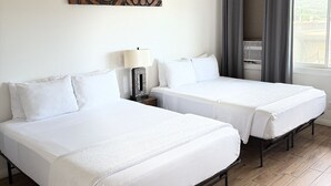 A hotel room with two beds, a ceiling fan, a wall-mounted artwork, a window with curtains, and a lamp. - Unit 16 Waena Inn - Maui Private Suite (Wailuku)
