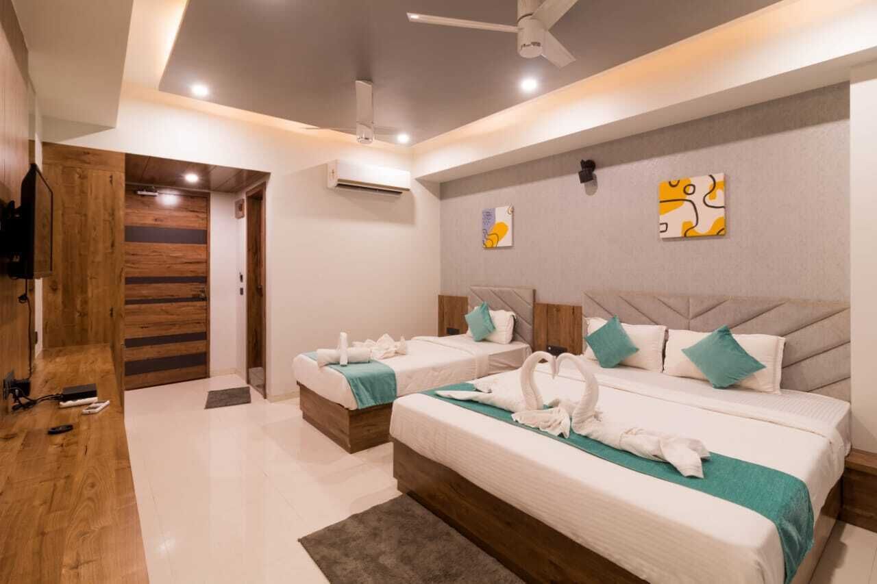A hotel room with two beds, a wooden door, and artwork on the wall.