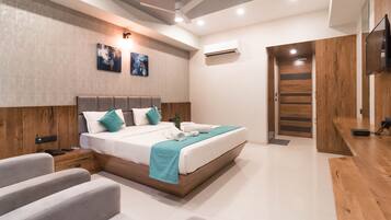 A modern bedroom with a large bed, a desk, and a TV.