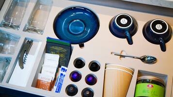 A kitchen counter with various items including glasses, plates, a spoon, a coffee cup, and packaged goods.