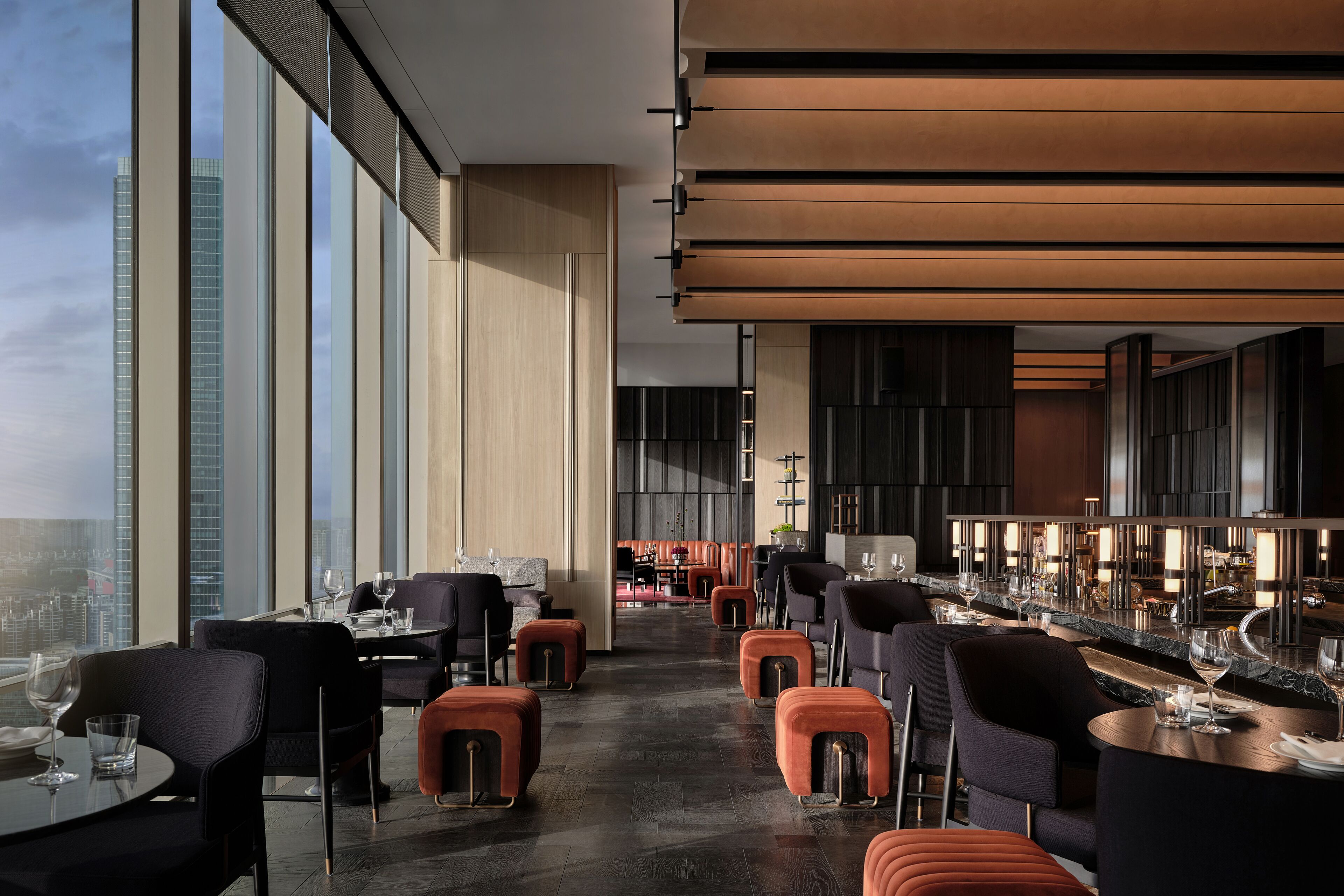 Un restaurant modern amb sostres alts, grans finestres i vista a la ciutat.