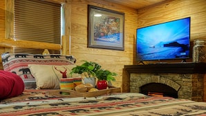Una habitación acogedora con cama, televisión, chimenea y un cuadro en la pared.