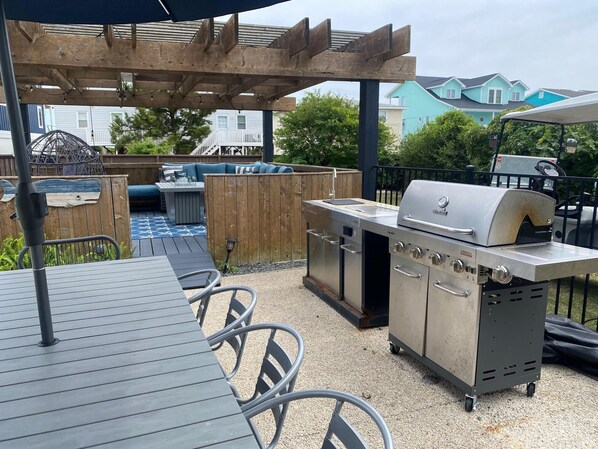 An outdoor patio with a grill, seating area, and a pergola.