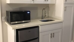 Una cocina con armarios blancos, microondas, fregadero y lavavajillas.