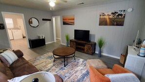 Ein Wohnzimmer mit Sofa, Hocker, Fernseher und Dekoration.
