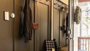 Un vestiaire moderne et minimaliste, doté d’un banc, de crochets pour suspendre les affaires et d’une porte donnant sur un espace extérieur.