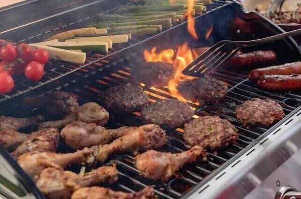 A grill with various meats and vegetables being cooked.