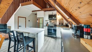 A modern kitchen with white cabinets, stainless steel appliances, and a wooden ceiling. - Deck & Grill: A-Frame Cabin in Munds Park! (Munds Park)