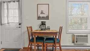 A dining area with a wooden table and four chairs, a coffee maker, and a framed picture on the wall. - Cozy & Chic Pocono Cabin | Firepits | Pickleball (Barrett Township)
