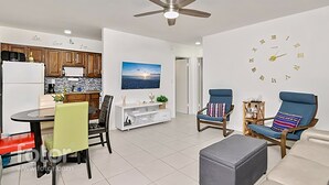 A modern living room with a dining area, kitchen, and a large wall clock. - Fully remodeled 1/1 apartment (Marco Island)
