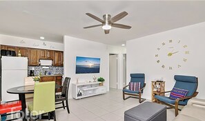 Una sala de estar moderna con comedor, cocina y un gran reloj de pared.