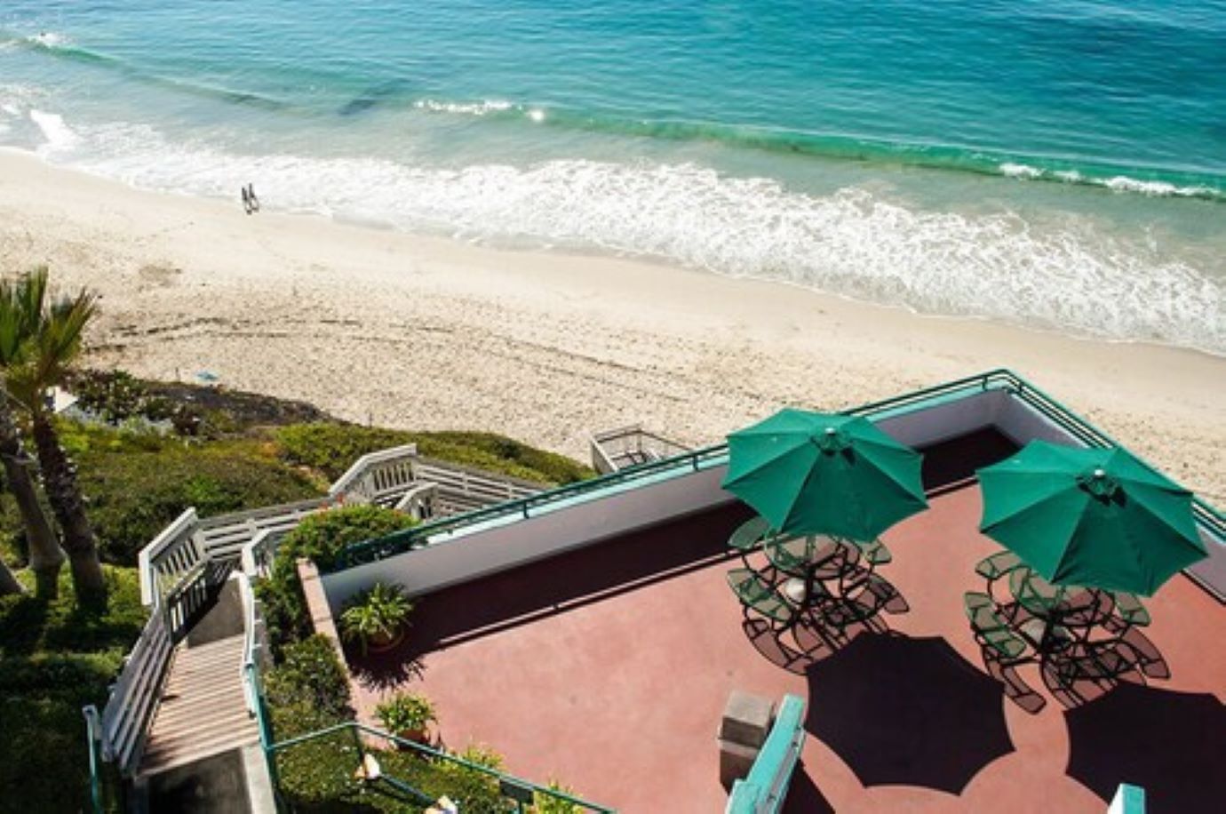 A beachside patio with outdoor seating and a view of the ocean.
