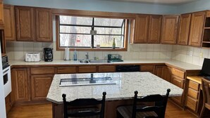 Una cocina con armarios de madera, encimera de granito y ventana sobre el fregadero.