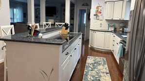 A modern kitchen with white cabinets, granite countertops, and a central island.