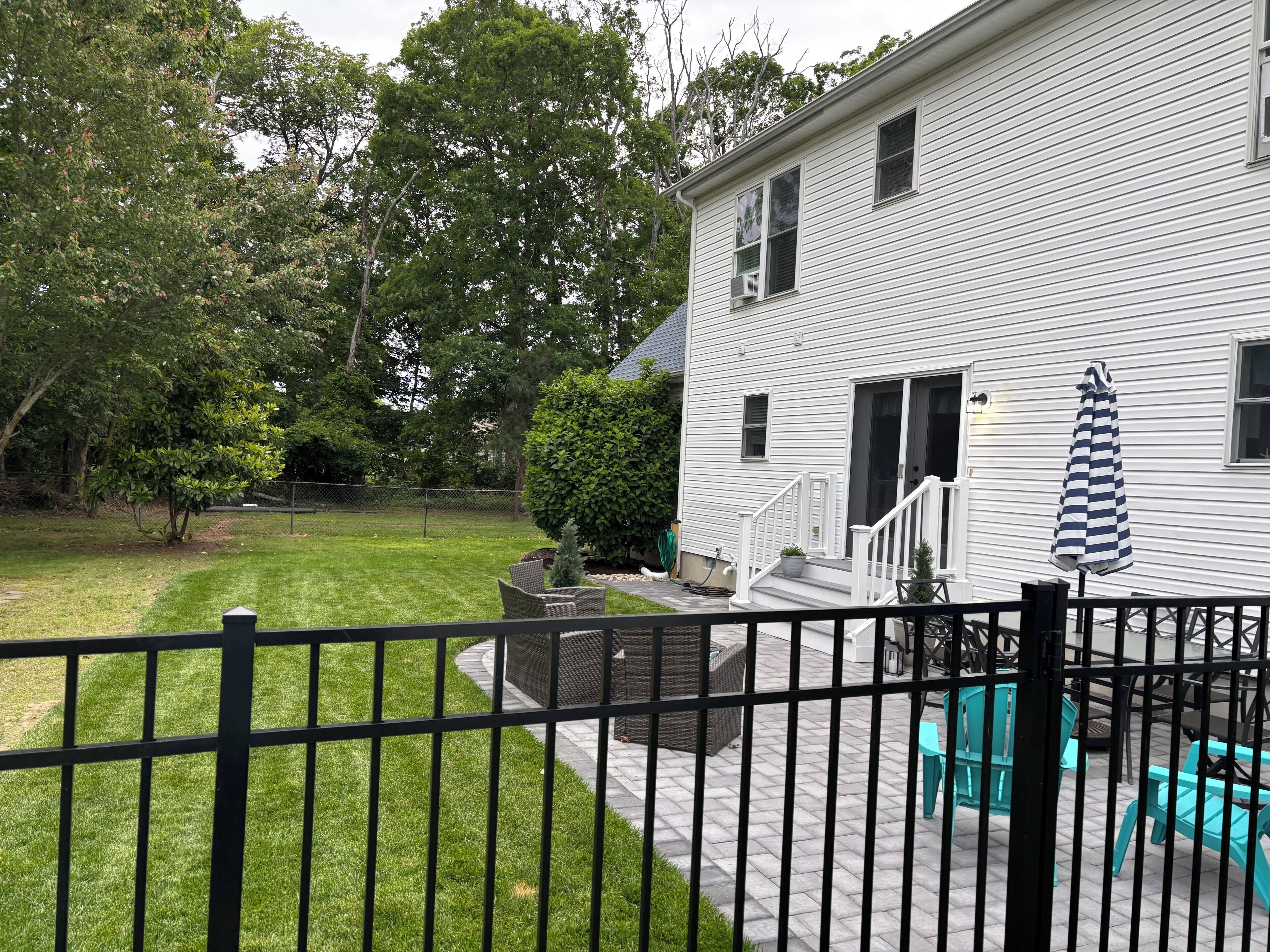 A white house with a covered patio, outdoor furniture, and a fenced yard.
