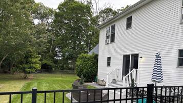 A white house with a covered patio, outdoor furniture, and a fenced yard.