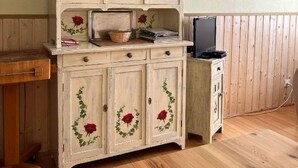 Un meuble en bois avec des portes en verre, une petite table et un ordinateur portable posés sur un plancher en bois.
